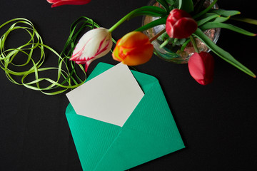 colored tulips and envelope on black background