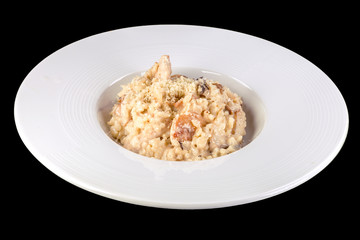 Tasty risotto with mushrooms in a white plate, isolated on black background