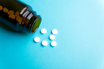 white round pills and jar with pills, blue background
