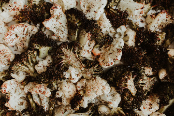 Healthy roasted and baked broccoli and cauliflower on a white baking tray. Lots of spices, chilli, pepper, salt. Mix of delicious vegetables. 