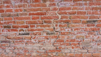 Red brick pattern. Old brick wall with cracks and scratches. Horizontal background of wide brick wall. Disturbed wall with broken brick texture. Vintage house facade.