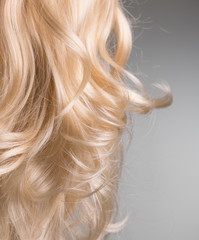 Blond Hair. Beautiful healthy long curly blonde hair close-up texture. Dyed Wavy white hair...