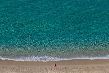 Girl on the beach in summer near clear blue sea. Copy space. Top view