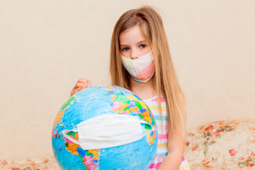 little girl in a medical mask holds a globe in her hands, wrapped in a medical mask. Little girl...