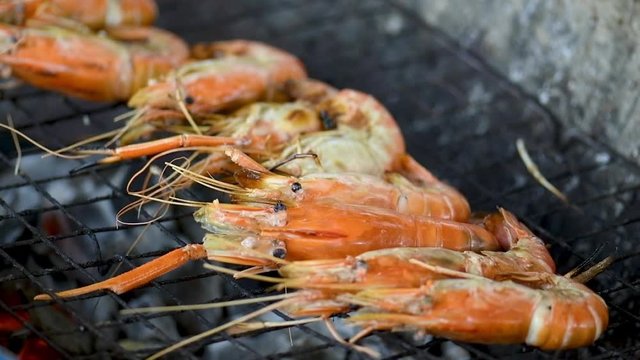 Delicious Grilled Prawns or Shrimps on Barbecue Grill. chef is cooking delicious prawn and burnt shrimp grill with flames on oven stove eat with seafood sauce,Fresh Asian Thai street sea food.  