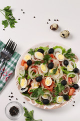 Healthy salad with canned tuna, tomatoes, quail eggs, black olives, white onions and organic lettuce on white background, Top view