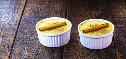 homemade corn candy, porridgeknown in Brazil as Curau, with cinnamon powder and cinnamon bark, rustic wood background.