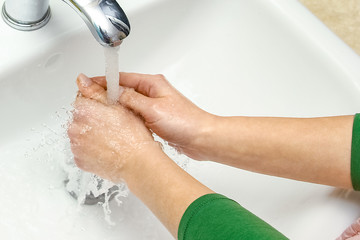 A Hands with soap are washed under the tap with water. Clean from infection and dirt and virus. At...
