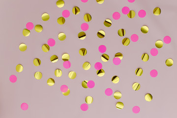 Golden and pink confetti on pink background. Happy birthday concept. Decorations, top view, copy space.