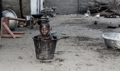 African child cools down in a bucket of water during a hot afternoon. Photo from a fishing village...