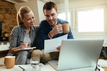Happy couple making their home budget while going through finances together.
