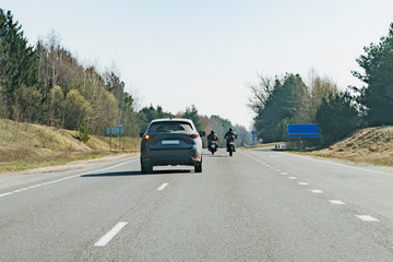 A passenger car overtaking motorcyclists