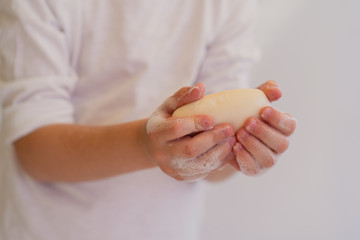 Baby washes his hands with white soap on a white background