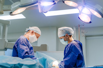 Group of surgeons in operating room with surgery equipment. Medical background