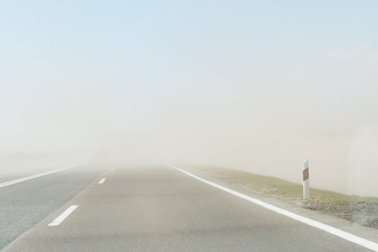 Strong Wind Carries Sand Across The Road