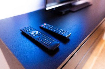 Remote Controls for Wireless Smart Television, DVD, DVB-T2, KI Plus, K1, KII Pro, DVB-S2, Android TV Box, Set-Top Box, HDTV, Satellite Receiver, Media Player on wooden TV stand against TV background