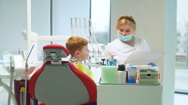 Female dentist writes on a medical card the symptoms of a boy patient. Safe Dentistry