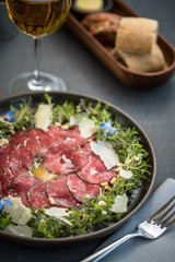 Carpaccio thin sliced beef meat with cheese, herbs