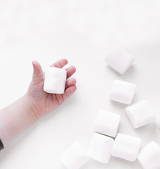 marshmallows in a children's hand on a white background, top view.
