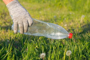 Volunteer cleaning up the garbage. A gloved hand cleans plastic bottles from a clearing. Ecology. Pure nature. Separate garbage collection. Stop plastic. Recycling. Zero waste.