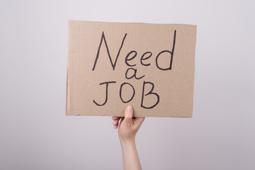 Need job concept. Cropped close up photo of hand arm holding carton placard with text isolated over grey background