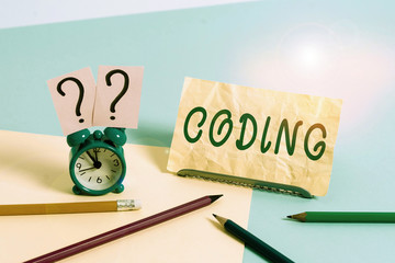 Word writing text Coding. Business photo showcasing assigning code to something for classification identification Mini size alarm clock beside stationary placed tilted on pastel backdrop