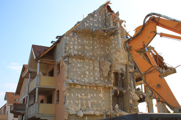 Fototapeta na wymiar House being demolished. Construction equipment. Rubbs of a dilapidated building. Destruction for reconstruction in the city. Broken and open facade.