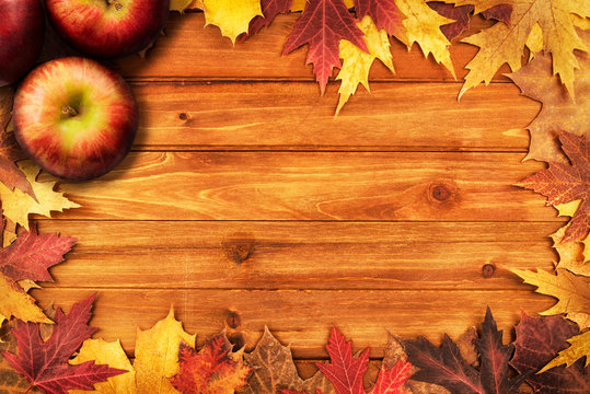 Apples and maple leaves disposed on a wooden table. Flat lay, top view of autumn decoration concept.