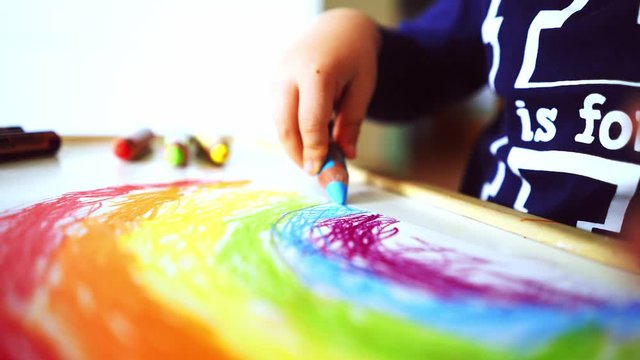Kid draws a rainbow at home during confinament
