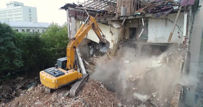 excavator machine destroying or demolishing building on construction site