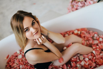 Obraz na płótnie Canvas Attractive blonde girl enjoys a bath with rose petals.