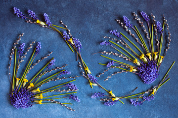 Abstract ornament of spring flowers muscari, primrose and pussy-willow twigs on a blue background