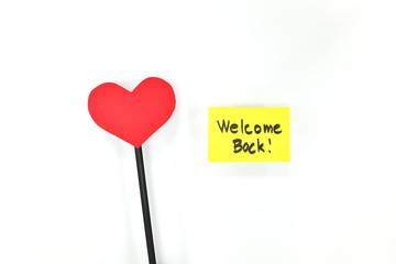 Yellow welcome back note with red heart. Back to work concept.