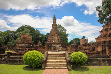 Buddha sitting raised on an altar through stairs and vegetation