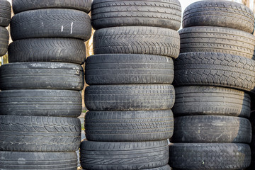 A stack of old rubber wheels lies on the street in several rows. Used black tires.