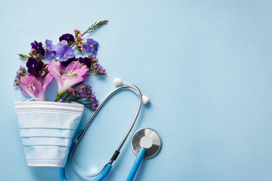 Flowers with mask and stethoscope on blue background. Happy nurse day concept. Top view