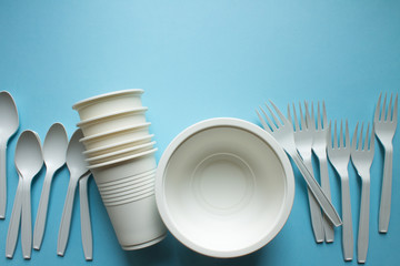 Biodegradable disposable tableware: plates, glasses and spoons with forks on a blue background...