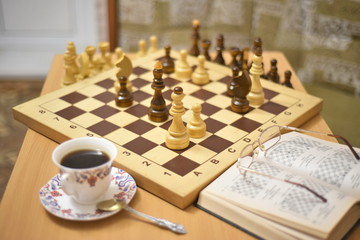 The decision of the chess game is postponed. Waiting for a Cup of coffee. Glasses are removed on the book.