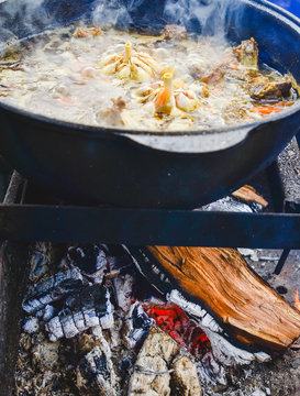 Pilaf on the cooking stage, zirvak with garlic, raisins, carrots, onions, lamb, barberry, saffron, zira and oil in a cauldron, boiling on the fire