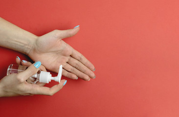 Using hand sanitizer alcohol gel on red background in Medical lab gloves. Clear sanitizer in pump bottle, for killing germs, bacteria. Corona Virus pandemic protection by washing hands frequently
