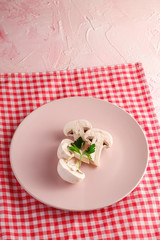 Champignon mushrooms healthy food in pink plate with parsley greenery on red tablecloth on pink textured background, angle view