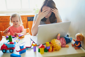 Exhausted and stressed mother working from home with toddler