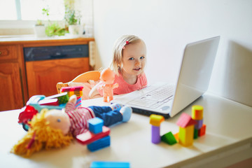 Happy toddler girl with laptop and toys