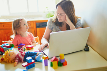 Exhausted and stressed mother working from home with toddler