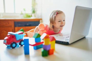Happy toddler girl with laptop and toys