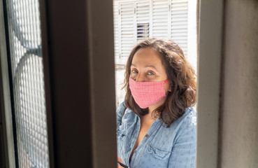 Latin woman protecting herself from the pandemic coronavirus, with the chinstrap done manually