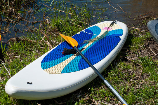white inflatable surfboard by the river