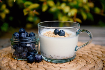 Eating a healthy breakfast. Yogurt, granola, chia seeds, fresh and dry fruits, blueberries in a transparent. Clean food, diet, detox, vegetarian food concept.