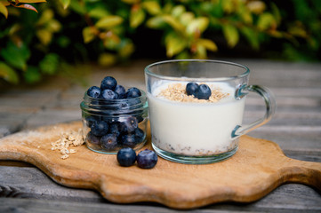 Eating a healthy breakfast. Yogurt, granola, chia seeds, fresh and dry fruits, blueberries in a transparent. Clean food, diet, detox, vegetarian food concept.