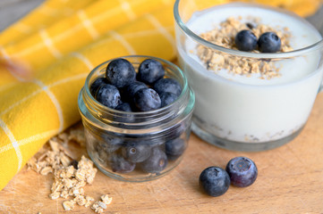 Eating a healthy breakfast. Yogurt, granola, chia seeds, fresh and dry fruits, blueberries in a transparent. Clean food, diet, detox, vegetarian food concept.